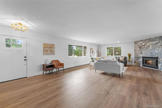 living room featuring light hardwood / wood-style flooring, a chandelier, and a high end fireplace