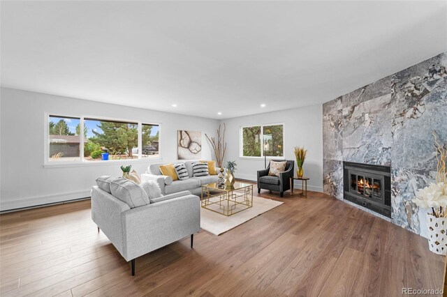 living room with a healthy amount of sunlight, a high end fireplace, and hardwood / wood-style flooring