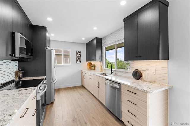 kitchen featuring light wood-type flooring, sink, tasteful backsplash, stainless steel appliances, and light stone countertops