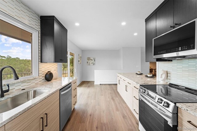 kitchen with light stone countertops, sink, appliances with stainless steel finishes, and light hardwood / wood-style floors