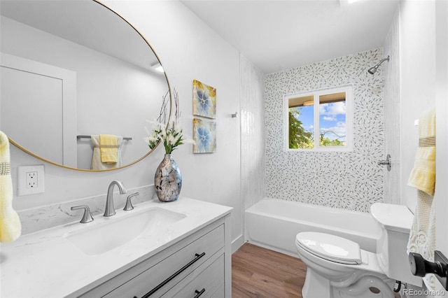 full bathroom with tiled shower / bath, vanity, hardwood / wood-style floors, and toilet