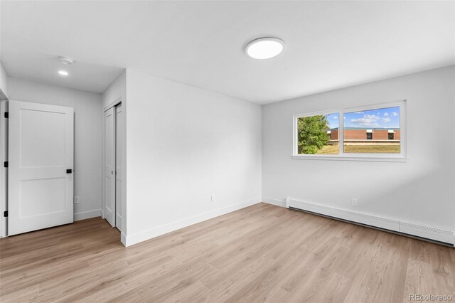 empty room with a baseboard radiator and light hardwood / wood-style flooring