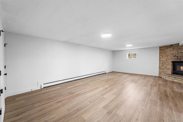 unfurnished living room with a fireplace, a baseboard heating unit, and light hardwood / wood-style flooring