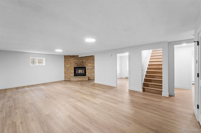 unfurnished living room with a stone fireplace and light hardwood / wood-style flooring