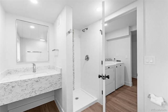 bathroom featuring washing machine and dryer, vanity, hardwood / wood-style floors, and tiled shower