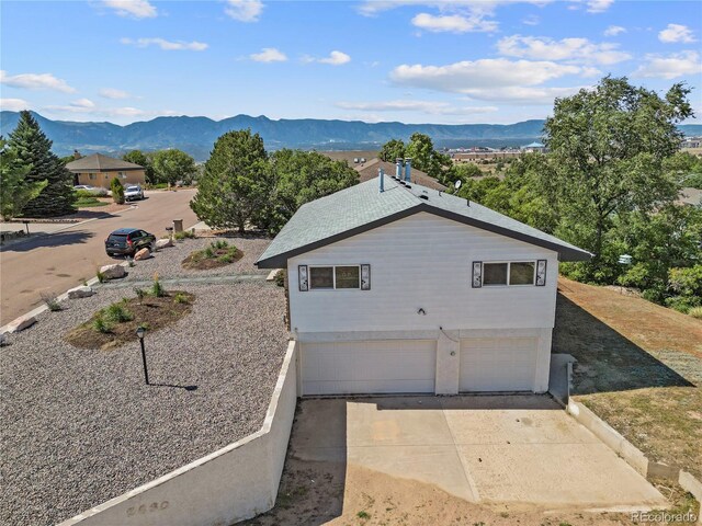 view of side of home with a mountain view and a garage