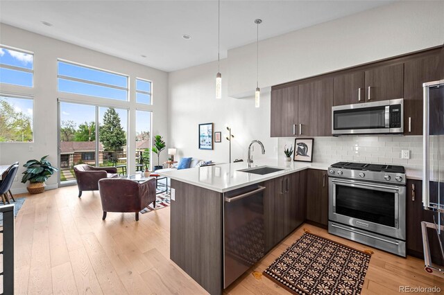 3480 E 31st Ave, Denver, CO 80205 - kitchen with stainless steel appliances, a sink, open floor plan, a peninsula, and dark brown cabinetry