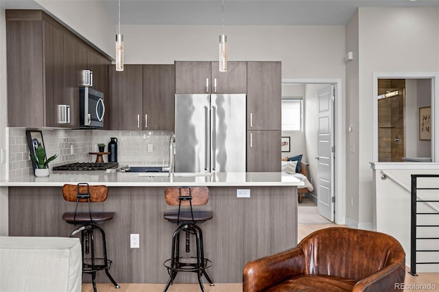 3480 E 31st Ave, Denver, CO 80205 - kitchen with stainless steel appliances, a peninsula, a sink, light countertops, and a kitchen breakfast bar