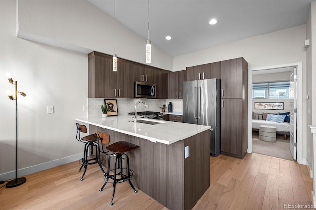3480 E 31st Ave, Denver, CO 80205 - kitchen with appliances with stainless steel finishes, a breakfast bar area, dark brown cabinetry, light wood-style floors, and a sink
