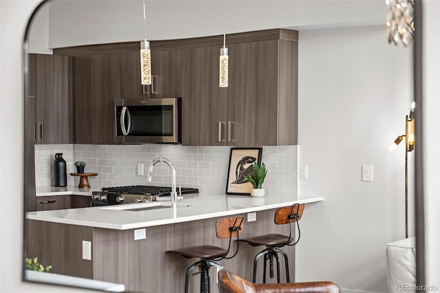 3480 E 31st Ave, Denver, CO 80205 - kitchen featuring stainless steel microwave, tasteful backsplash, a kitchen breakfast bar, light countertops, and modern cabinets
