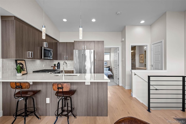 3480 E 31st Ave, Denver, CO 80205 - kitchen featuring stainless steel appliances, a sink, a peninsula, a breakfast bar, and light countertops