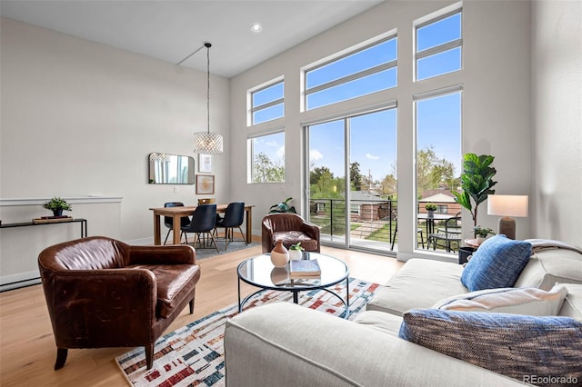 3480 E 31st Ave, Denver, CO 80205 - living room featuring light wood-style floors, a chandelier, a towering ceiling, baseboards, and recessed lighting