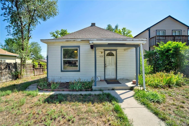 bungalow-style house with a porch, a shingled roof, and fence