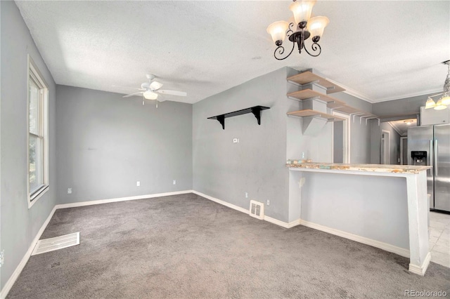 kitchen with ceiling fan with notable chandelier, stainless steel fridge, kitchen peninsula, and a textured ceiling