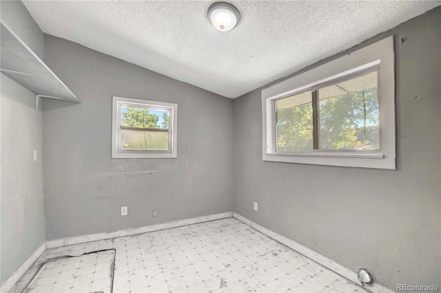 spare room with lofted ceiling and a textured ceiling