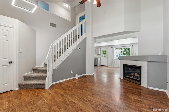 5441 Lynx St, Frederick, CO 80504 - stairs featuring wood finished floors, a ceiling fan, baseboards, a towering ceiling, and a tiled fireplace