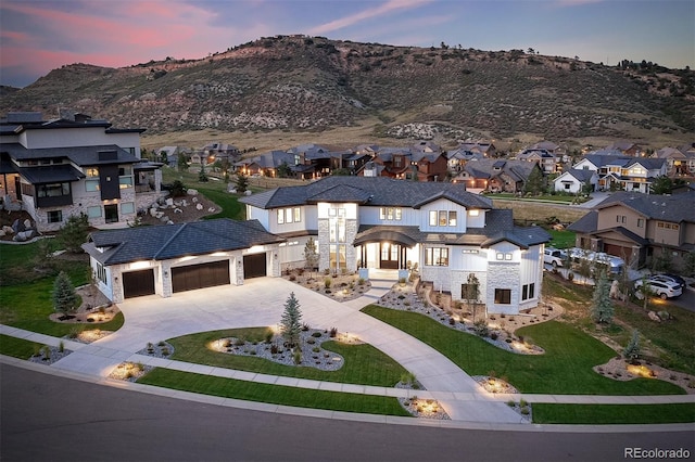 view of front of house featuring a lawn, an attached garage, a residential view, stone siding, and driveway