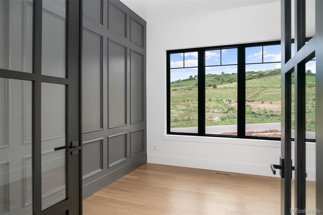 interior space with light wood-style flooring, multiple windows, baseboards, and a decorative wall