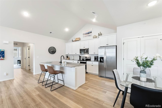 2078 Autumn Moon Dr Unit 3, Windsor, CO 80550 - kitchen featuring appliances with stainless steel finishes, a center island with sink, a breakfast bar, high vaulted ceiling, and white cabinetry