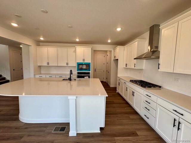 283 Wooten Ave, Brighton, CO 80601 - kitchen featuring wall chimney range hood, black appliances, white cabinets, an island with sink, and recessed lighting