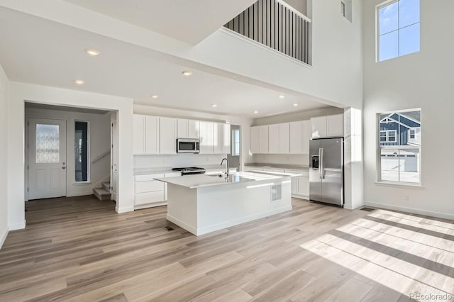 kitchen featuring a center island with sink, white cabinets, light hardwood / wood-style floors, and appliances with stainless steel finishes