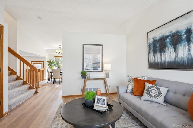living room with light wood-type flooring, stairs, a notable chandelier, and visible vents