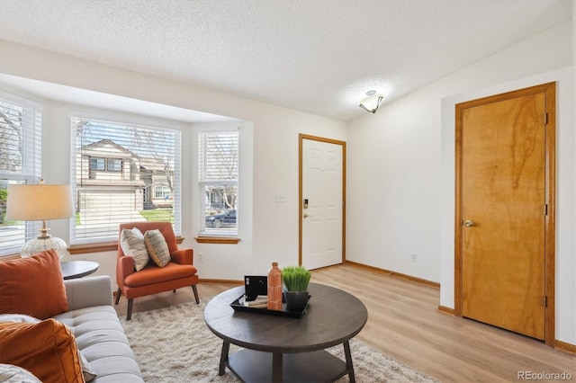 living area with a textured ceiling, a wealth of natural light, and light wood-style flooring