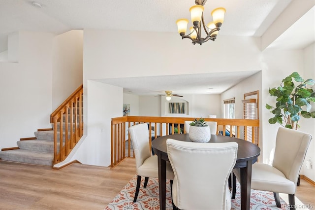 dining room with light wood-type flooring and ceiling fan with notable chandelier