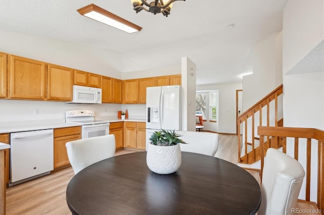 dining room with light wood-style floors, an inviting chandelier, stairway, and vaulted ceiling