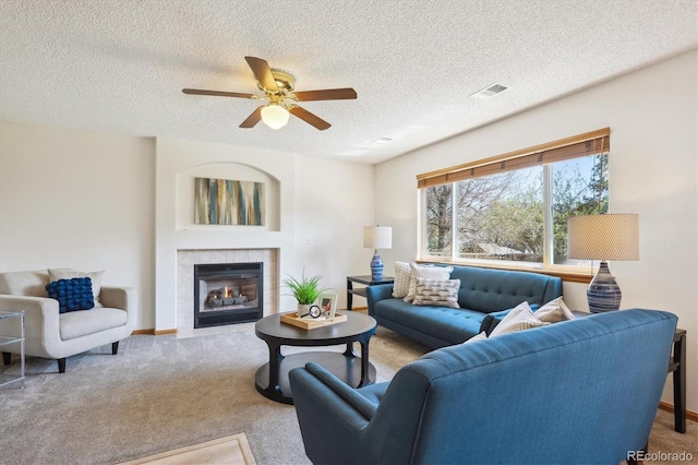 living room featuring ceiling fan, carpet, a textured ceiling, and visible vents