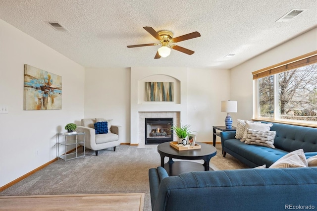 living room featuring baseboards, a ceiling fan, a tile fireplace, and visible vents