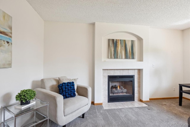 living area with carpet floors, a textured ceiling, baseboards, and a fireplace