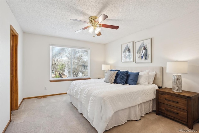 bedroom featuring visible vents, baseboards, ceiling fan, light colored carpet, and a textured ceiling