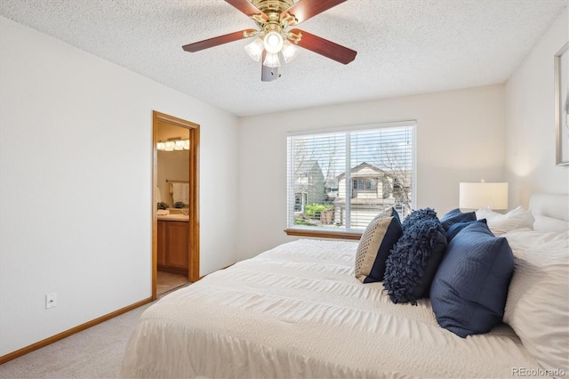 carpeted bedroom with baseboards, a textured ceiling, ceiling fan, and ensuite bathroom