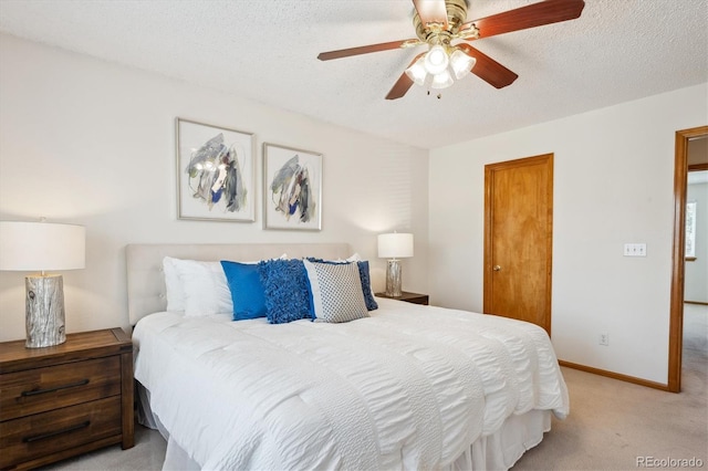 bedroom featuring a ceiling fan, light carpet, a closet, and a textured ceiling