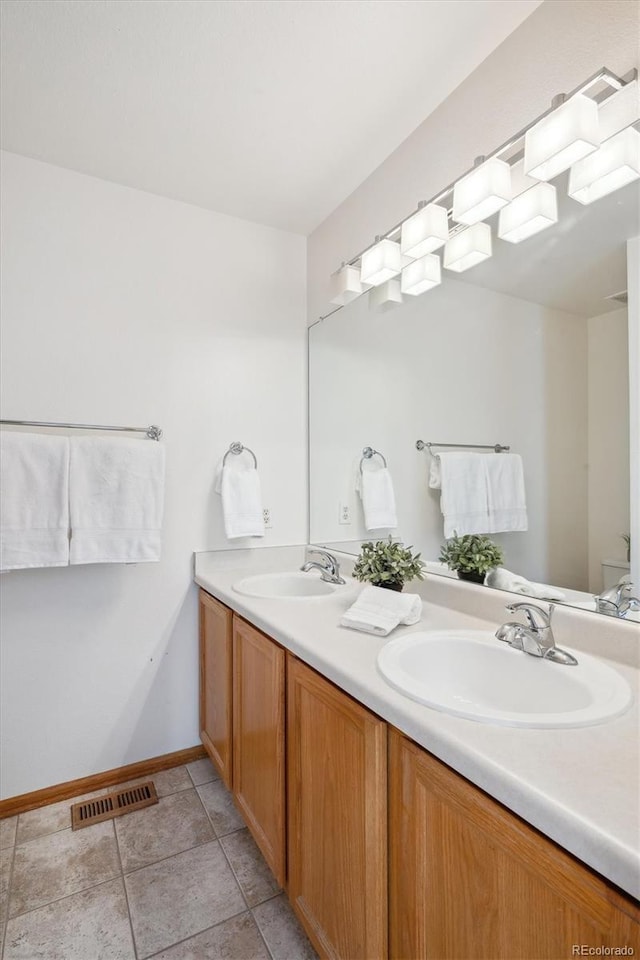 full bath featuring visible vents, a sink, baseboards, and double vanity