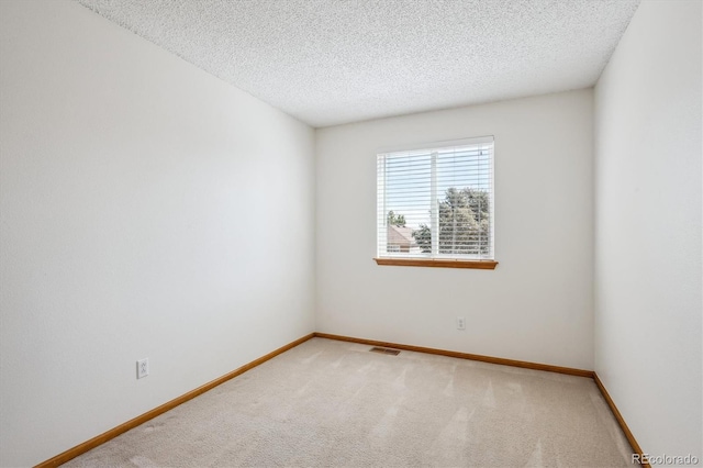 empty room with baseboards, carpet, a textured ceiling, and visible vents