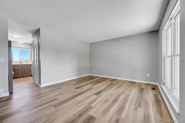 19155 E Kansas Dr, Aurora, CO 80017 - spare room with light wood finished floors, a sink, baseboards, and a textured ceiling