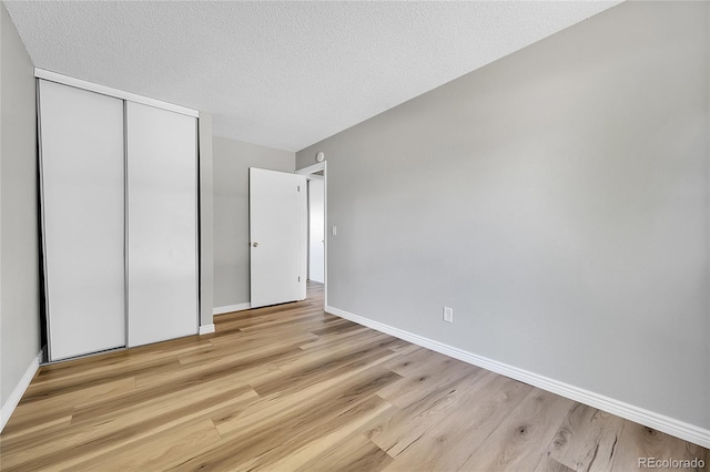 19155 E Kansas Dr, Aurora, CO 80017 - unfurnished bedroom with a closet, light wood finished floors, baseboards, and a textured ceiling