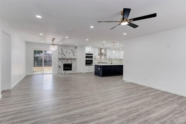 unfurnished living room with light wood-style flooring, recessed lighting, baseboards, and a sink