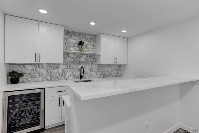 bar featuring a sink, decorative backsplash, beverage cooler, and recessed lighting