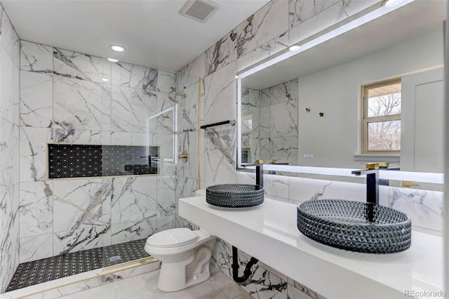 bathroom with a sink, a marble finish shower, toilet, and visible vents