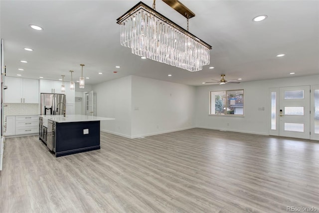 kitchen featuring open floor plan, light wood-style flooring, stainless steel fridge with ice dispenser, and light countertops