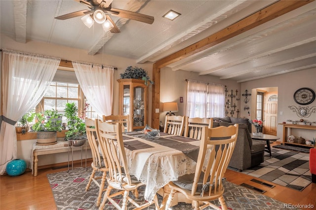 dining space with beamed ceiling, ceiling fan, and wood-type flooring