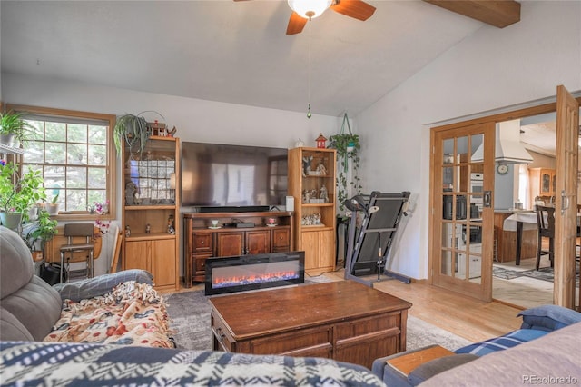 living room with ceiling fan, light hardwood / wood-style flooring, and vaulted ceiling with beams