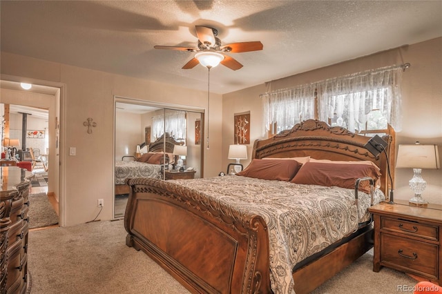 bedroom featuring ceiling fan, light carpet, a textured ceiling, and a closet