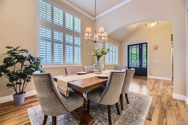 940 Kearney St, Denver, CO 80220 - dining area with arched walkways, a chandelier, light wood-style flooring, high vaulted ceiling, and crown molding
