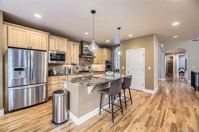 940 Kearney St, Denver, CO 80220 - kitchen with appliances with stainless steel finishes, wall chimney range hood, light brown cabinets, arched walkways, and decorative backsplash