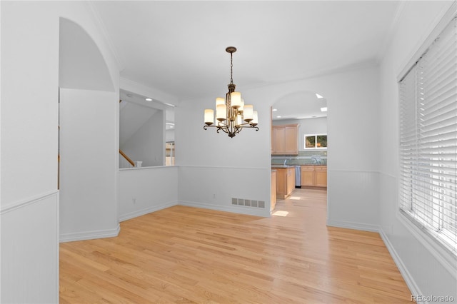 1172 S Steele St, Denver, CO 80210 - unfurnished dining area with a chandelier, light wood-style floors, arched walkways, and ornamental molding