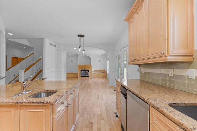 1172 S Steele St, Denver, CO 80210 - kitchen featuring stainless steel dishwasher, light wood-style flooring, a glass covered fireplace, backsplash, and light brown cabinets
